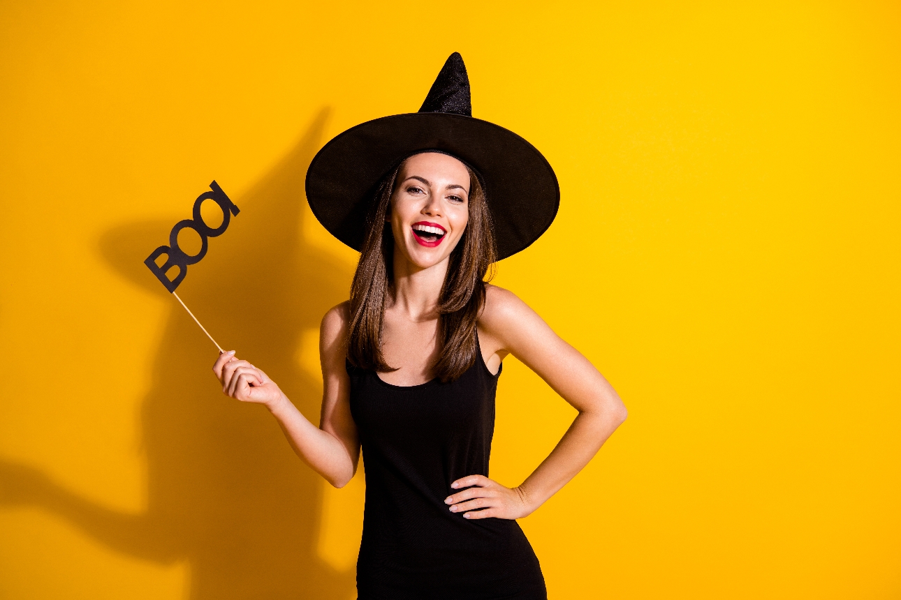 woman in black witch outfit with sign boo