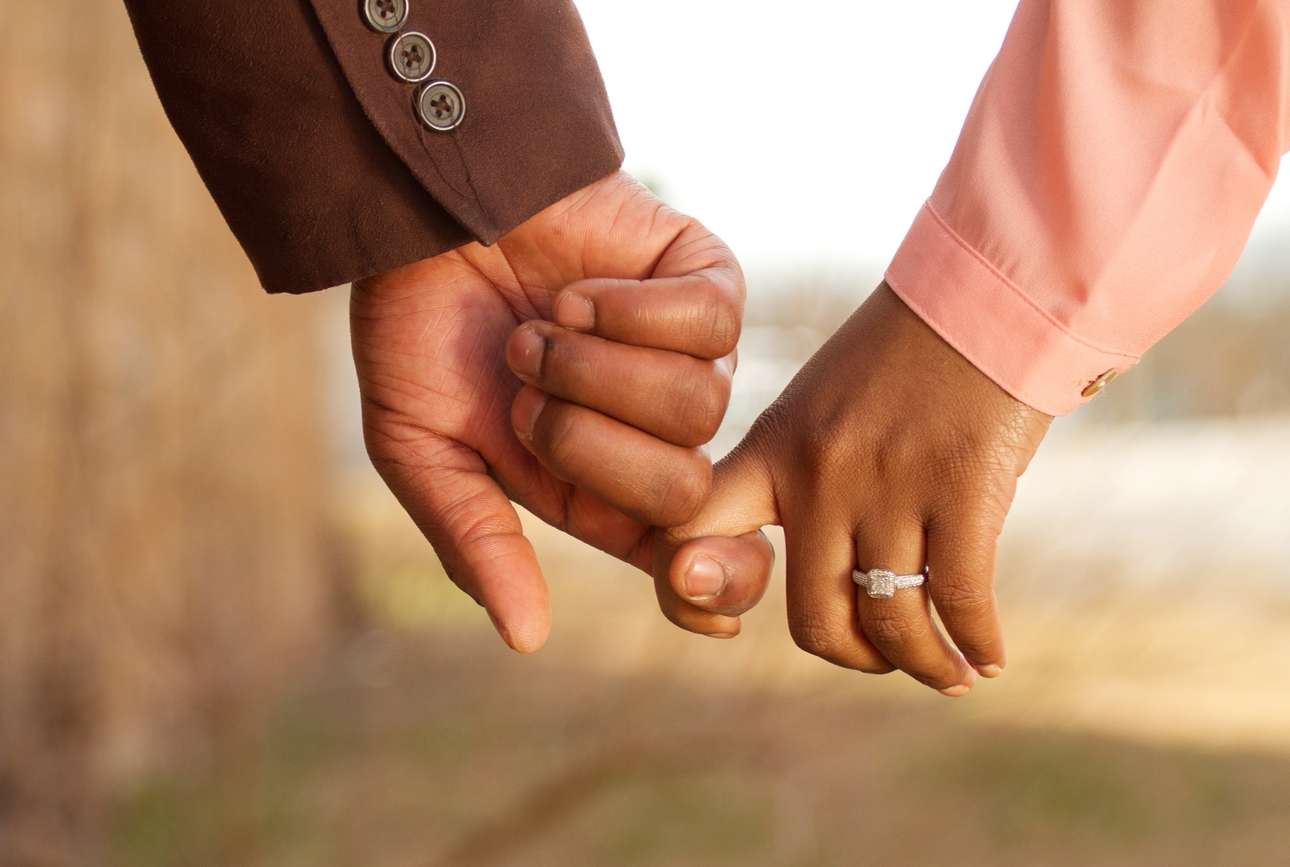 two hands holding one has engagement ring on 