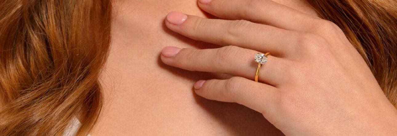 gold ring with oval diamond on hand hand touching neck