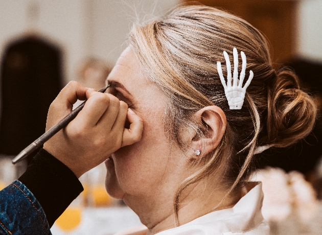 Halloween themed bride having her makeup done wearing a skeletal hand hair clip