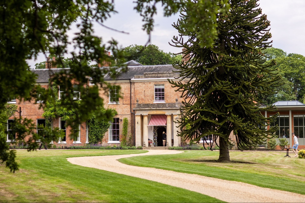 red brick manor house Elcot Park, winding gravel path to entrance, grass area and trees