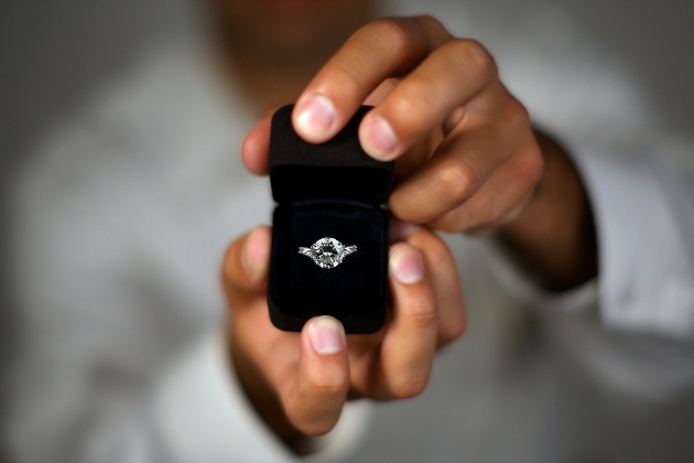 A man proposing and holding up an engagement ring