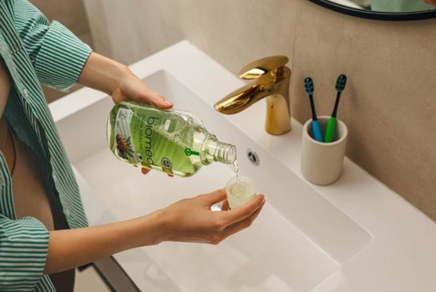 Person pouring mouthwash in to cup over sink