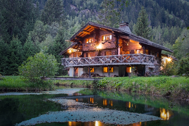 A large cabin in the middle of the woods overlooking a lake