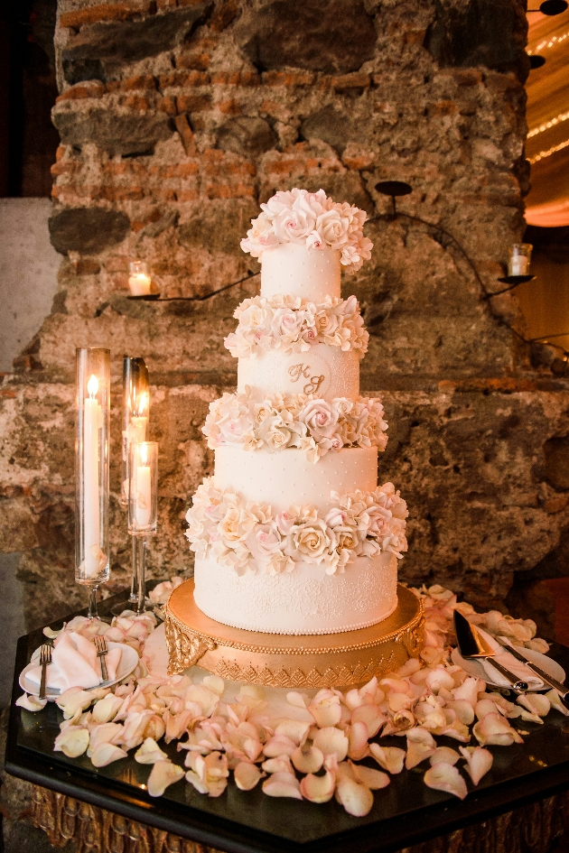 monogramed wedding cake decorated with roses.