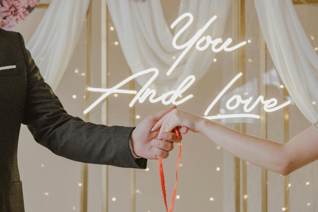 wedding handfasting with you and love neon sign in background