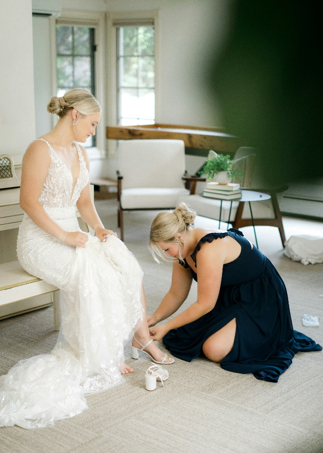 maid of honour helping bride with her shoes