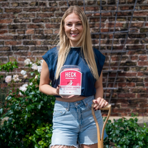 women holding a shovel and a pack of Heck's wedding sausages