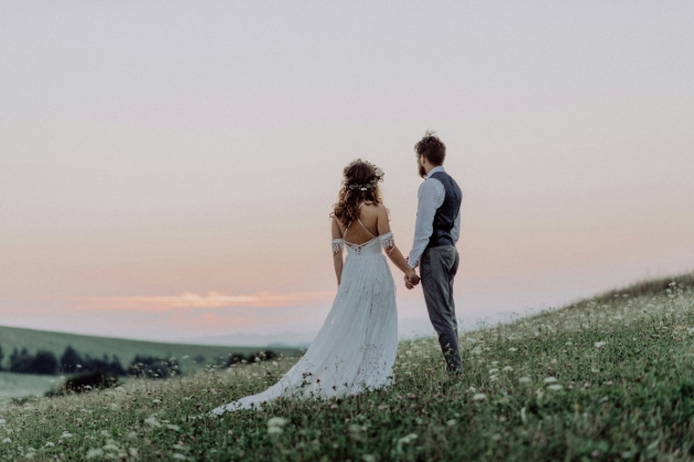 couple holding hands looking off into the distant facing a countryside view