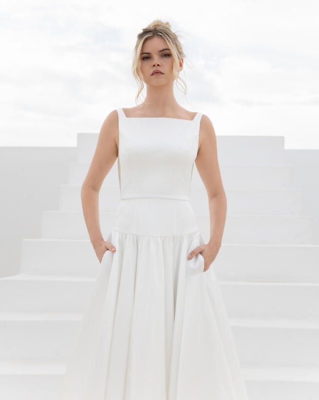 A duchess satin gown with a boat neckline and striking deep V-back that showcases sculpted panel lines on the bodice