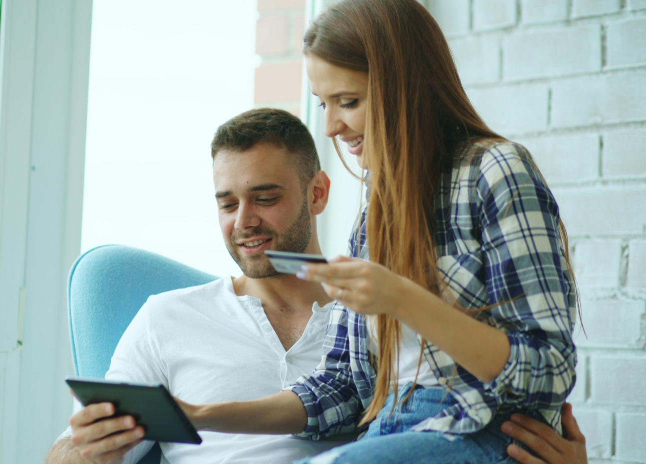 woman sat on man's lap booking something on an ipad