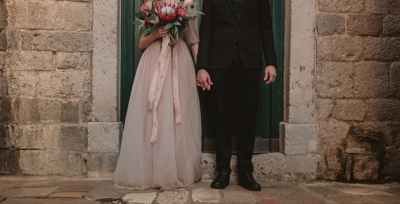 married couple holding hand in front of church 